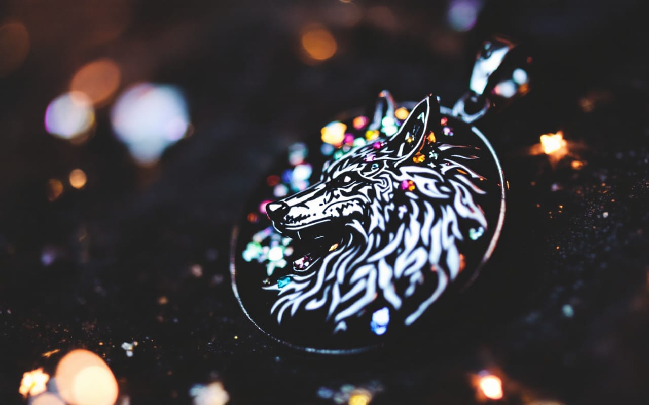 Gros plan d'un pendentif avec un motif de loup, montrant des d&eacute;tails en argent et des pierres pr&eacute;cieuses scintillantes sur un fond sombre.